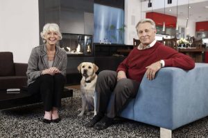 Barrierefreiheit: Ehepaar im hohen Alter sitzen mit ihrem Hund im Wohnzimmer